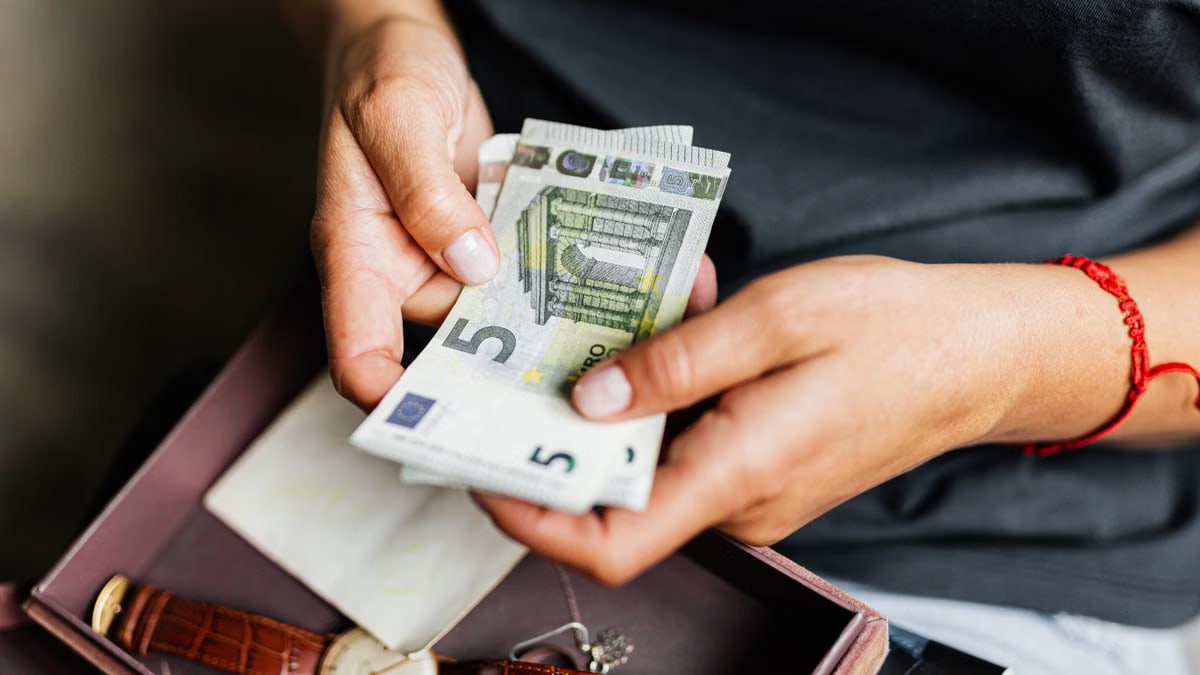 Close-up of hands counting euro notes above a wristwatch in a box.